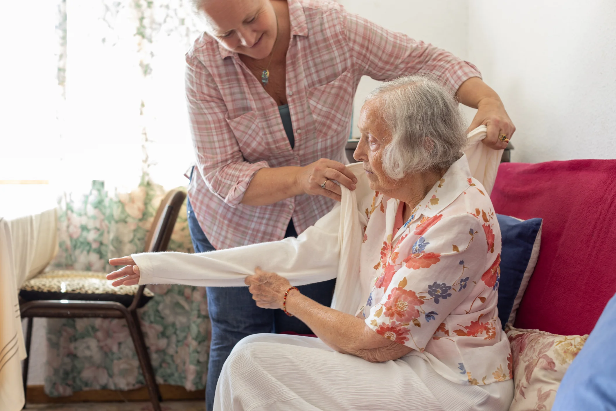 Home health aide helping an elderly woman get dressed in the comfort of her own home
