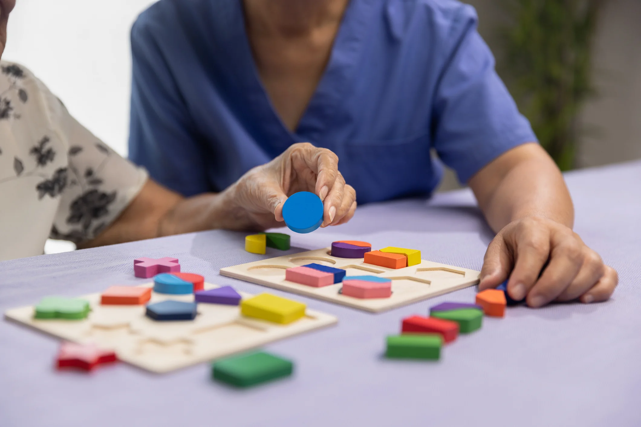 Memory care therapist guiding an elderly patient through a cognitive puzzle activity for dementia support